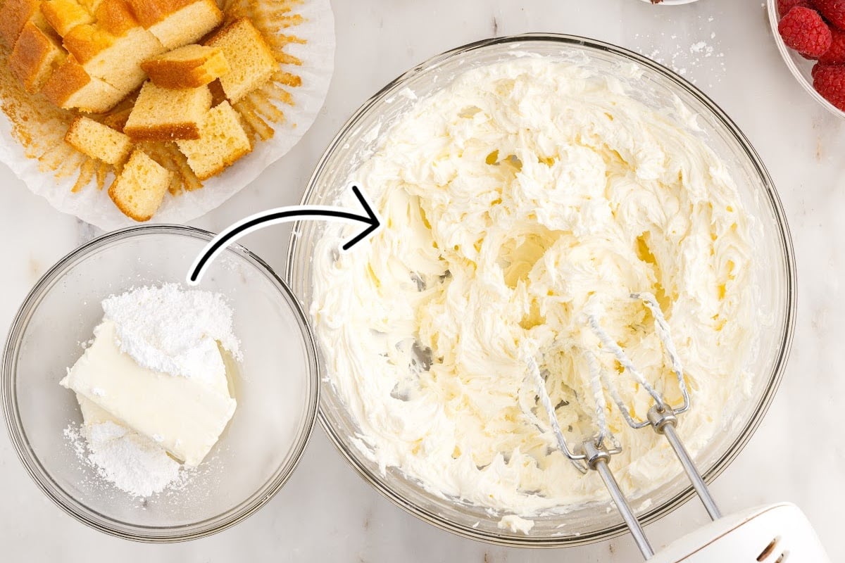 Cream cheese and powdered sugar in a bowl and a second bowl of cream cheese mixture with hand mixer inserted next to angel food cake.
