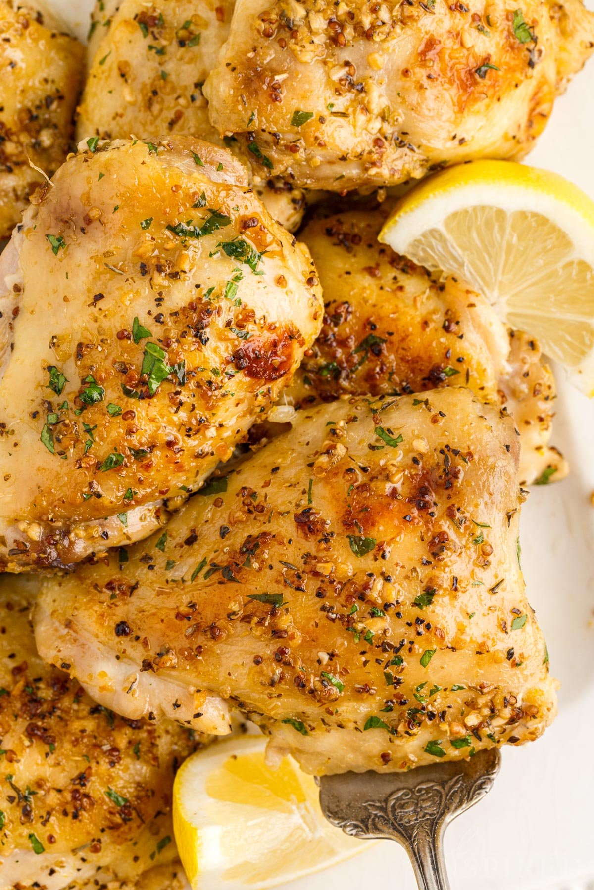 Baked Chicken Thighs on a plate with lemon slices.