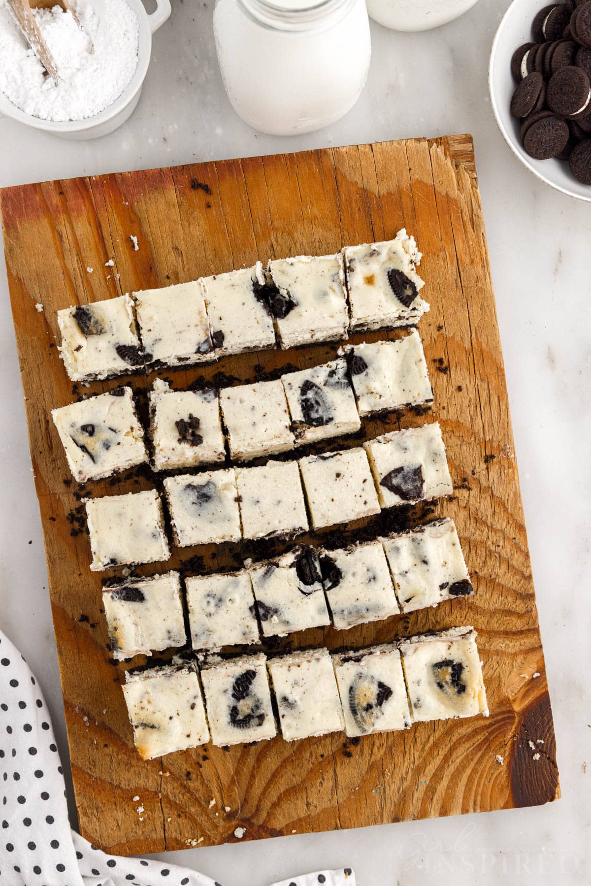 A wooden cutting board with Oreo Cheesecake Bites on it cut into pieces.