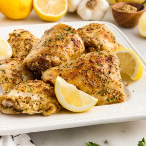 A plate of Baked Chicken Thighs with lemon slices.