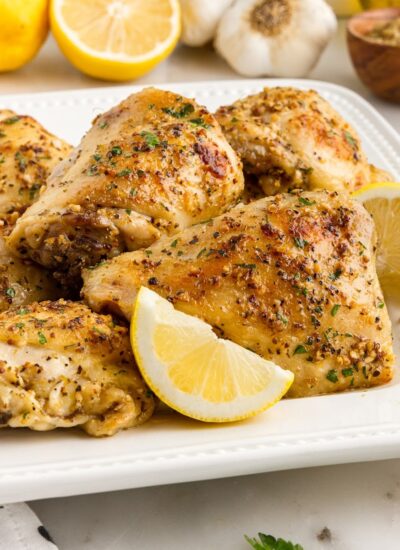 A plate of Baked Chicken Thighs with lemon slices.