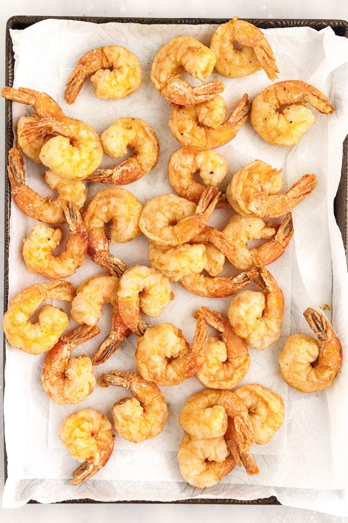 Buffalo Shrimp on a parchment paper lined cookie sheet after being deep fried.