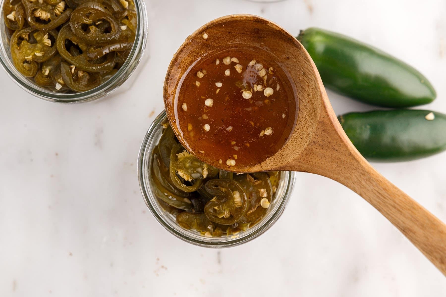 Candied Jalapeños brine drizzled in a jar of Candied Jalapeños.