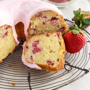 Strawberry Bundt Cake with slices cut and a slice in front on a cooling rack.