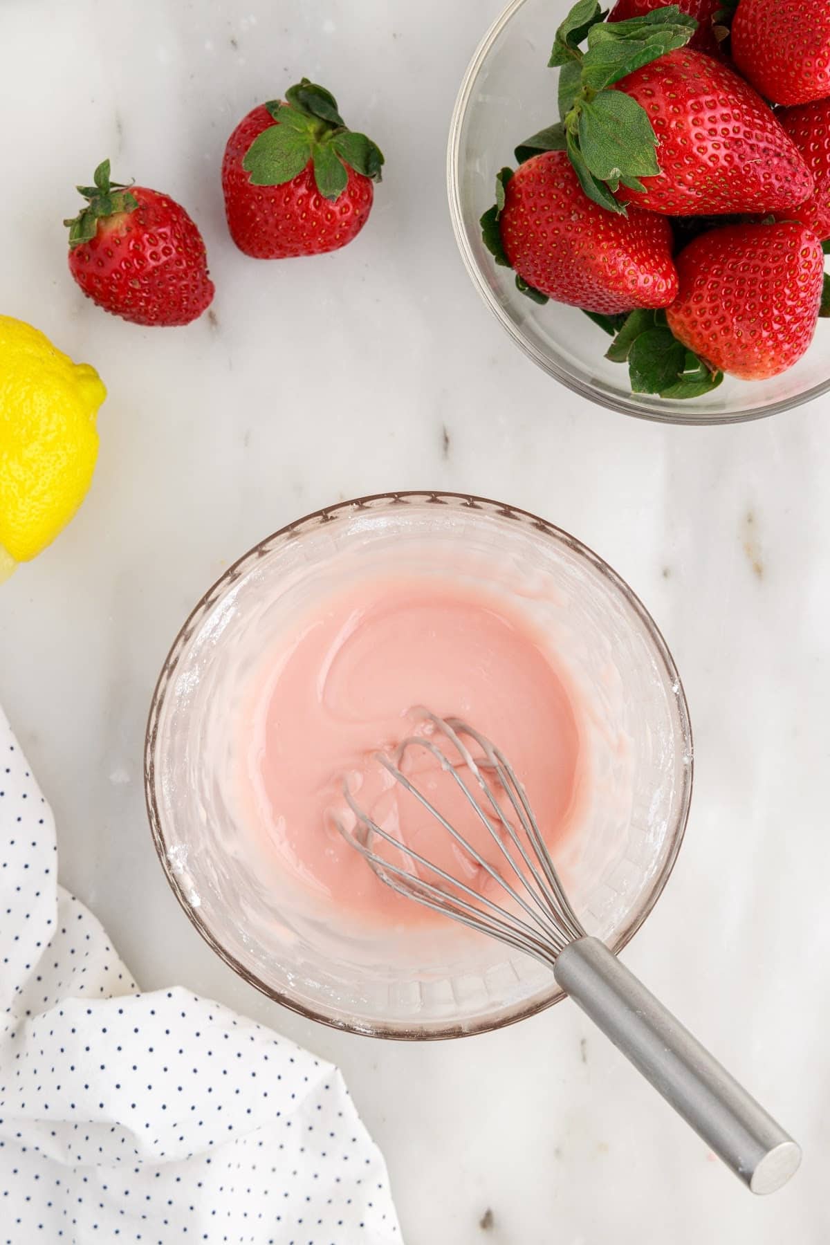 Glaze mixture stirred together with a whisk next to strawberries.