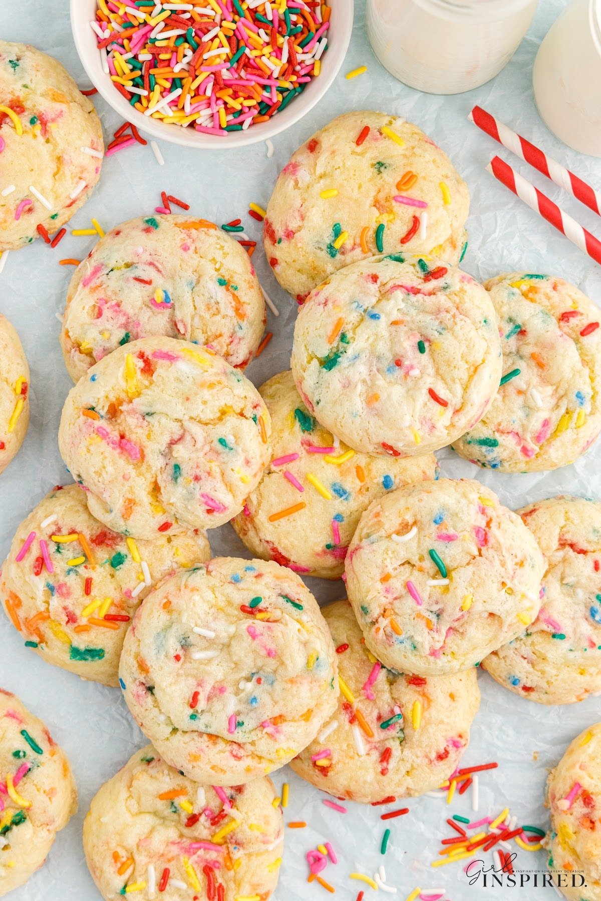 Confetti Cake Mix Cookies on parchment paper next to a bowl of sprinkles.