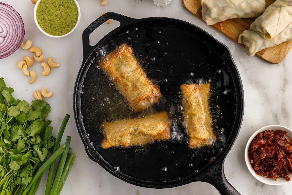 Cheesecake Factory Avocado Egg Rolls in a skillet of oil after being fried.