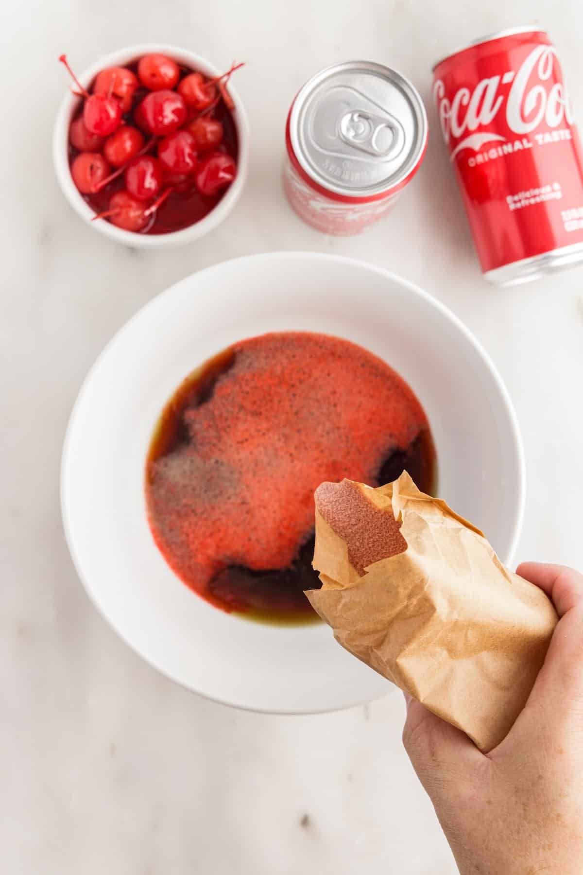 Jello powder poured into hot Coca-Cola in a bowl.