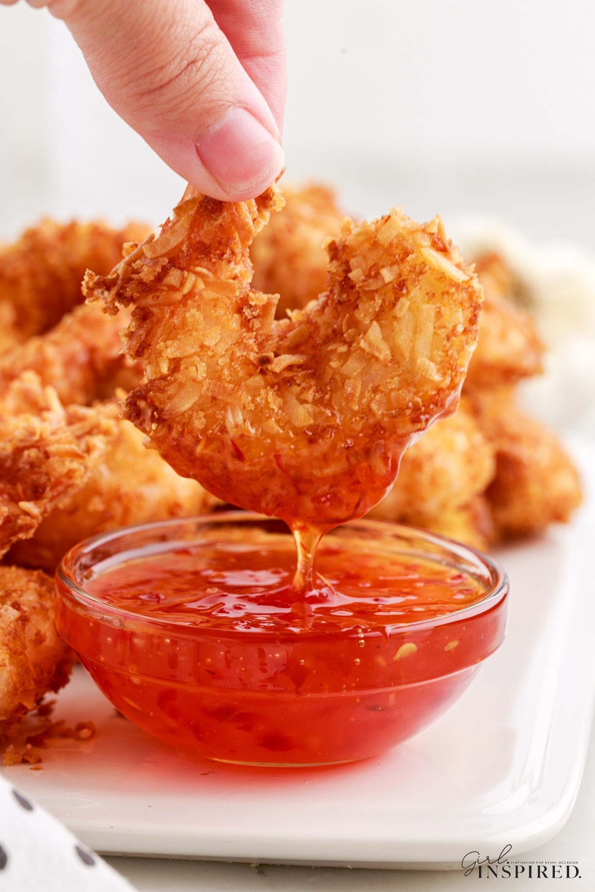 A piece of Coconut Fried Shrimp dipped in sauce.