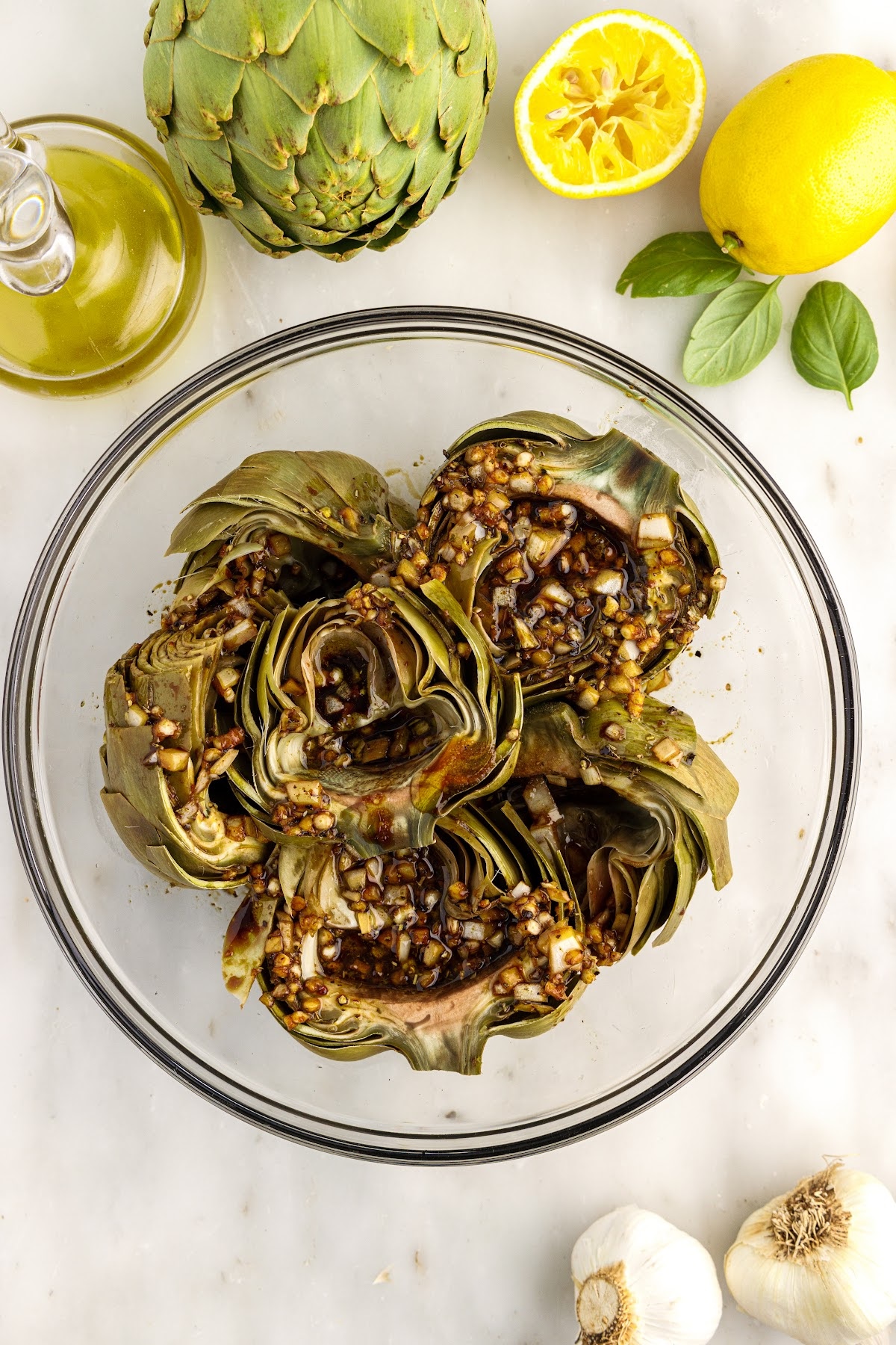 Grilled Artichokes in a mixing bowl with seasonings on the top.