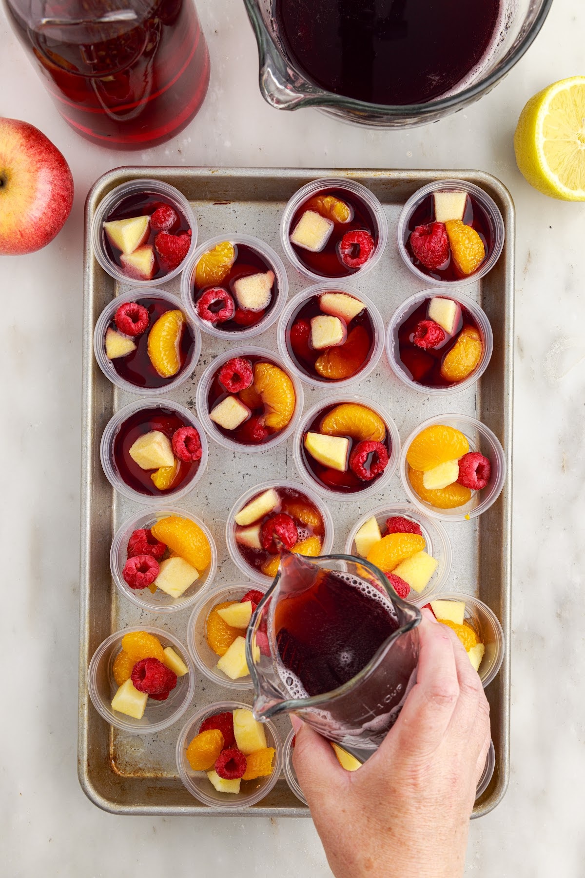 Tray of shot glasses being filled with Sangria mixture.