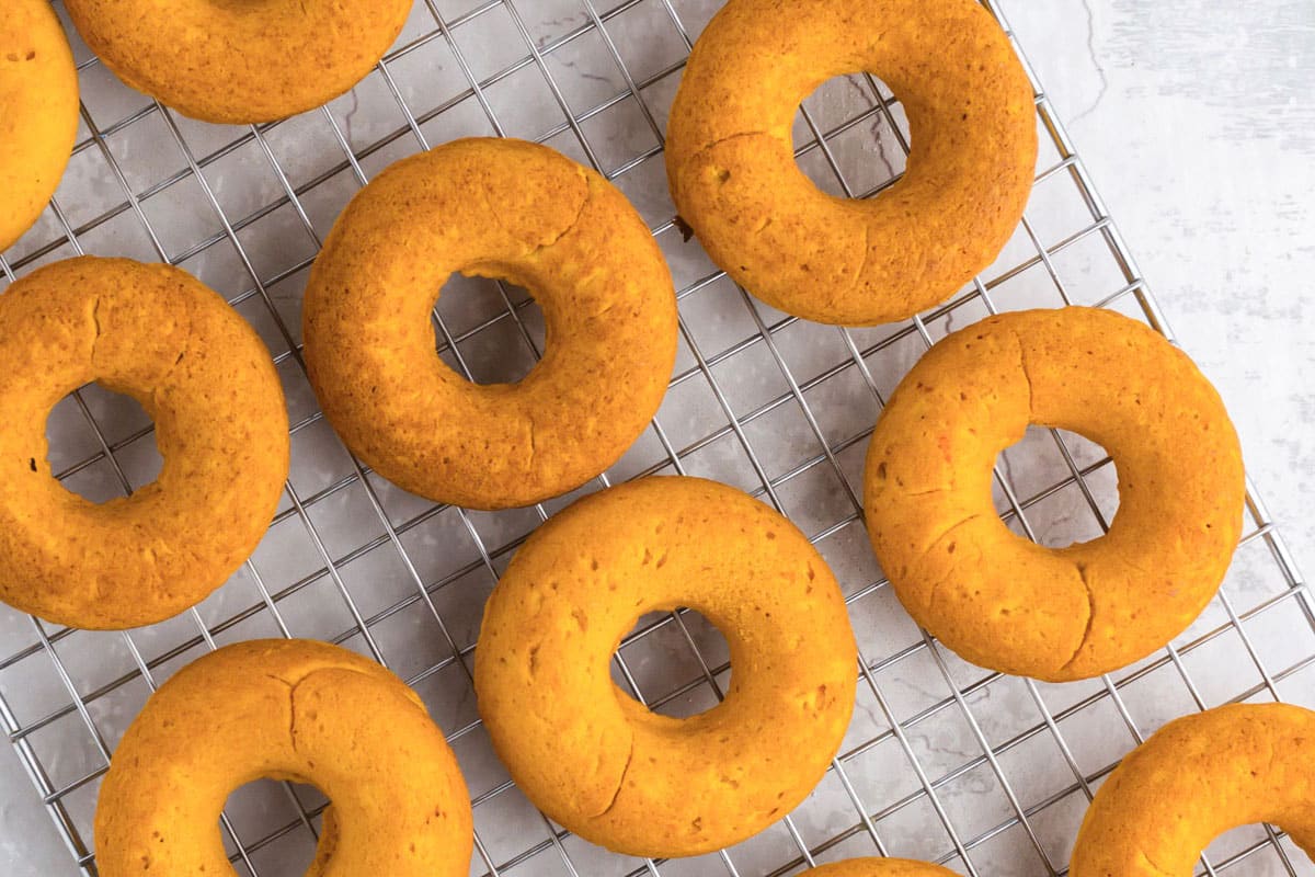 Baked pumpkin donuts on cooling rack.