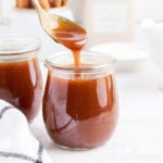 Starbucks Dark Caramel Sauce in a small clear cup, dripping off of a spoon.
