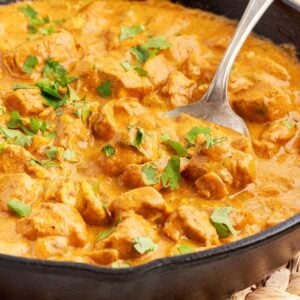 Close up of a skillet of Curry Chicken with a serving spoon inserted.