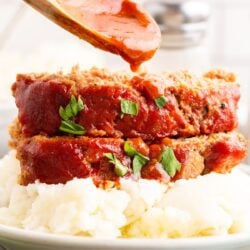 Close up of mashed potatoes topped with two slices of Mama's Meatloaf.