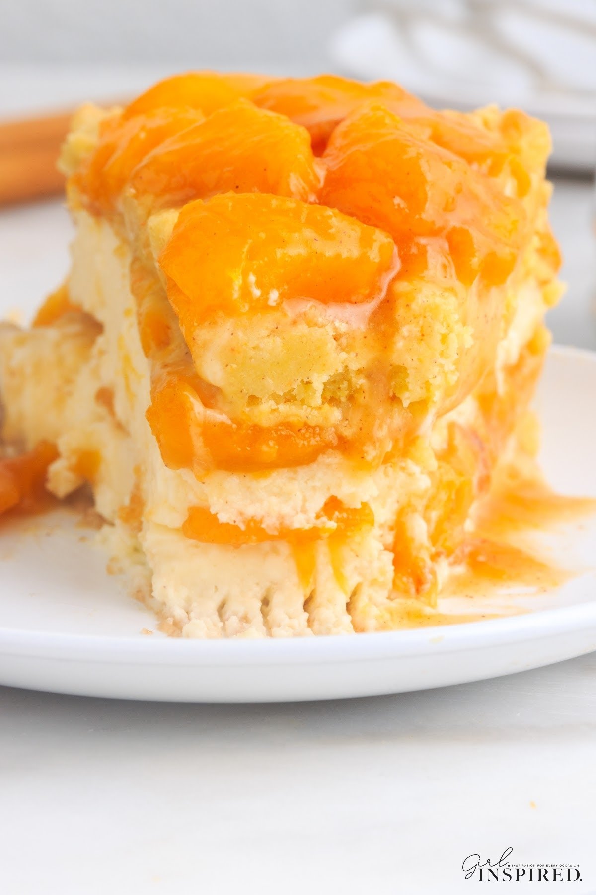 A slice of Peach Cobbler Cheesecake on a plate with a bite taken from the front.