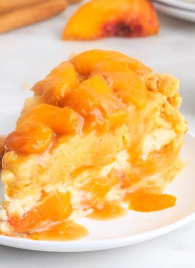 A slice of Peach Cobbler Cheesecake on a plate.