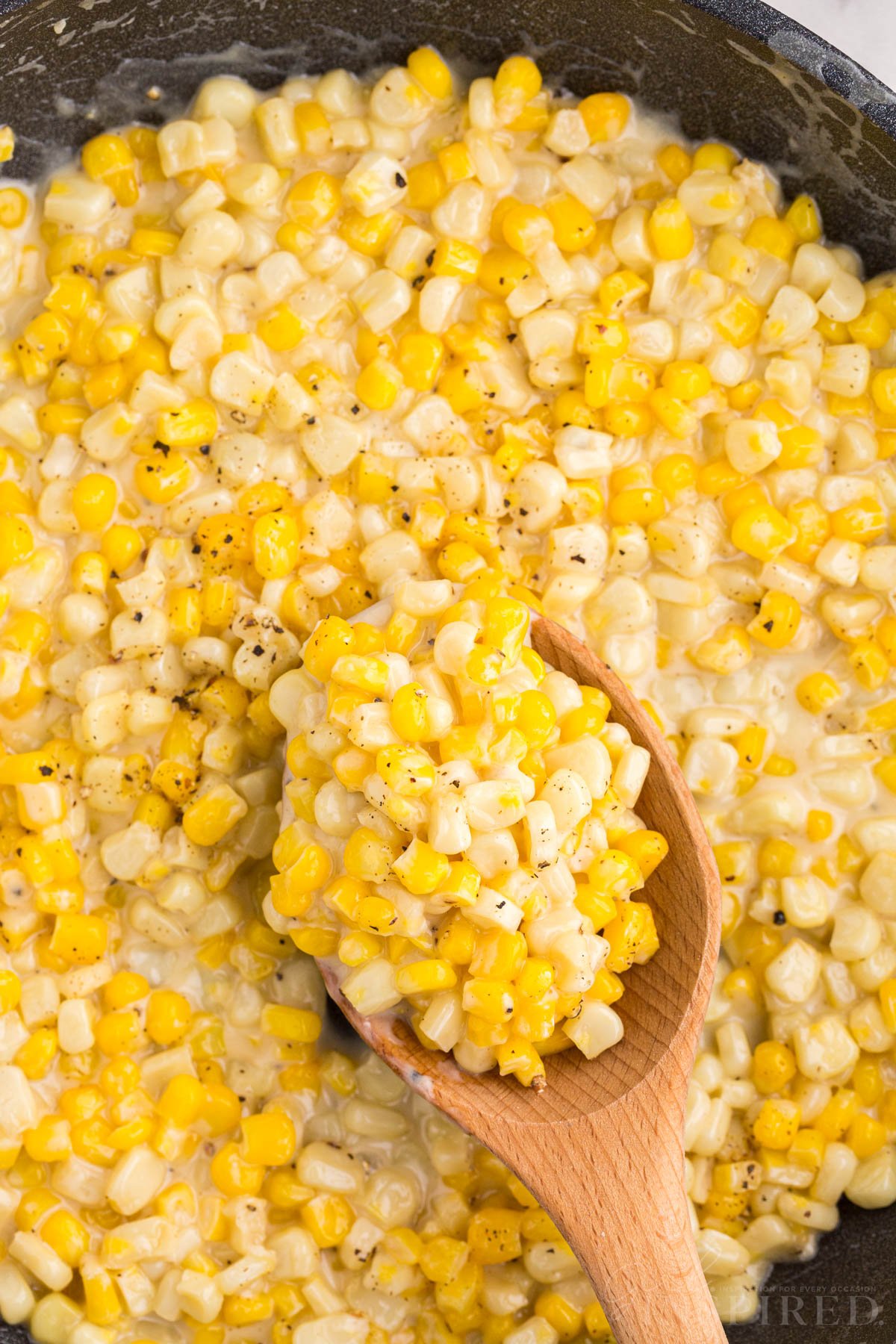 Overhead close up of Honey Butter Skillet Corn with some on a wooden spoon.