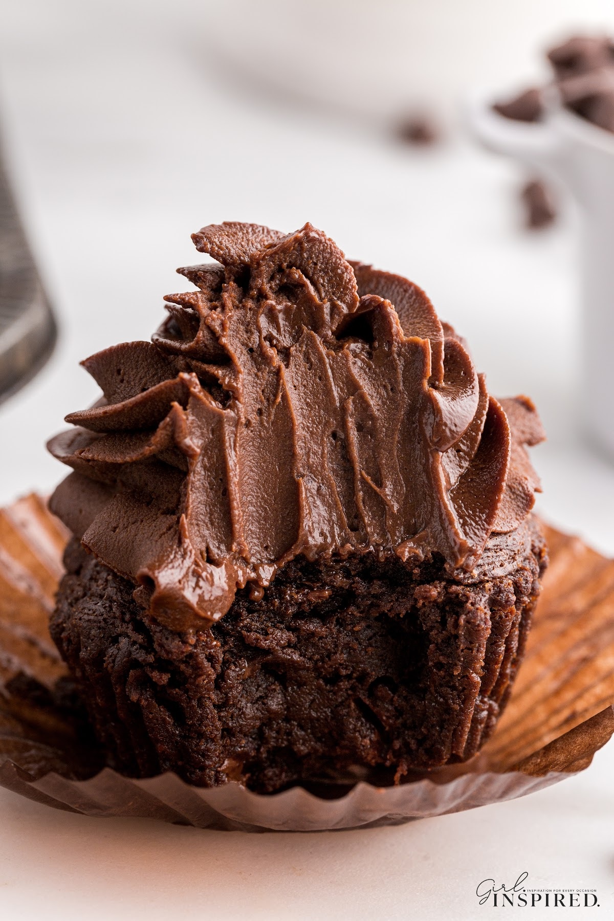 A chocolate cupcake topped with Whipped Chocolate Ganache with a bite taken from it.