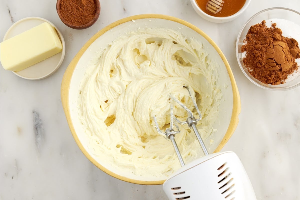 Cream cheese vanilla and sugar mixed in a mixing bowl with a hand mixer.