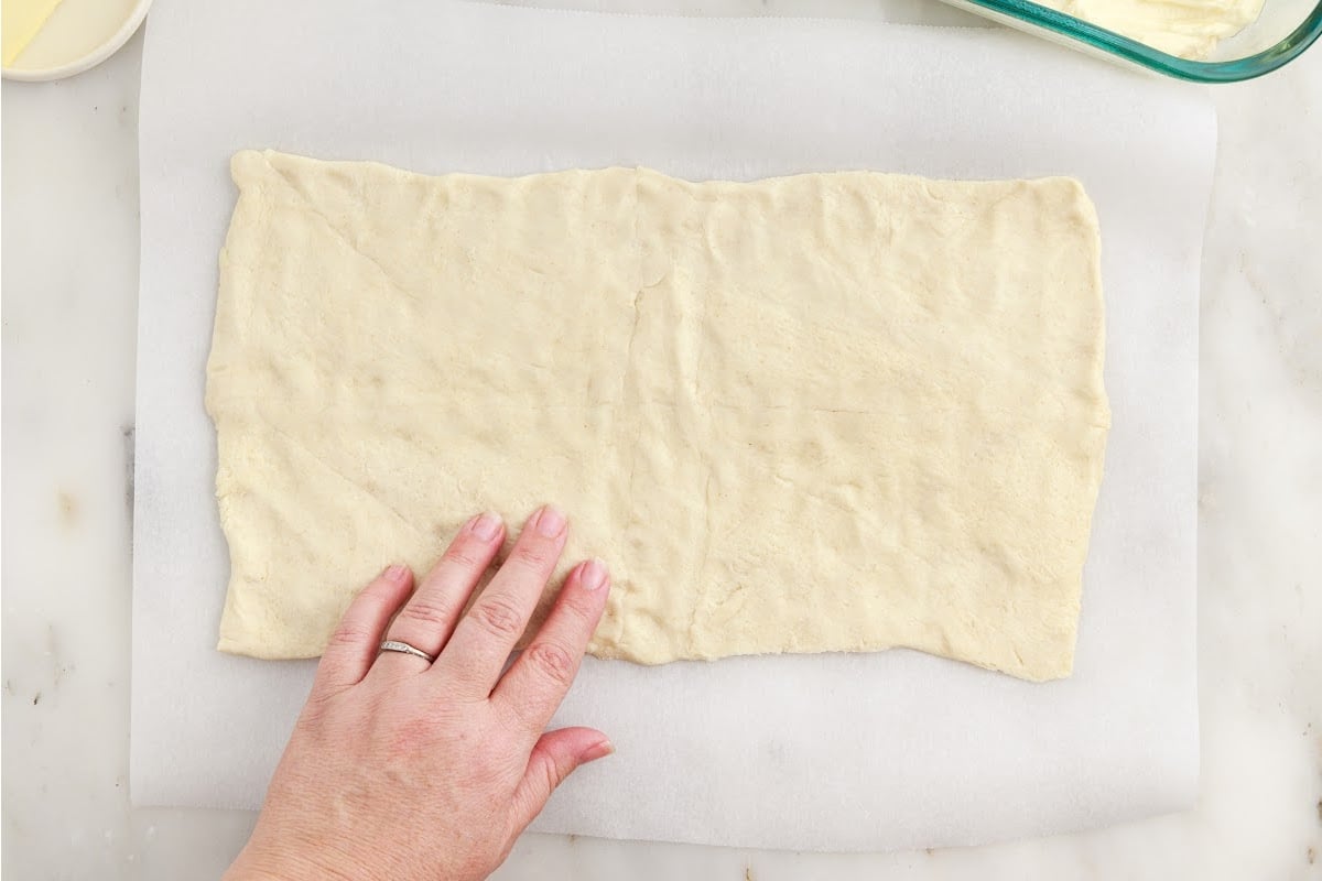 Crescent rolls rolled out onto parchment paper.