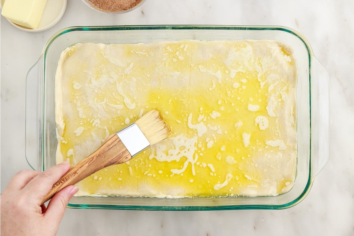 Melted butter spread on the top of the Sopapilla Cheesecake with a brush.