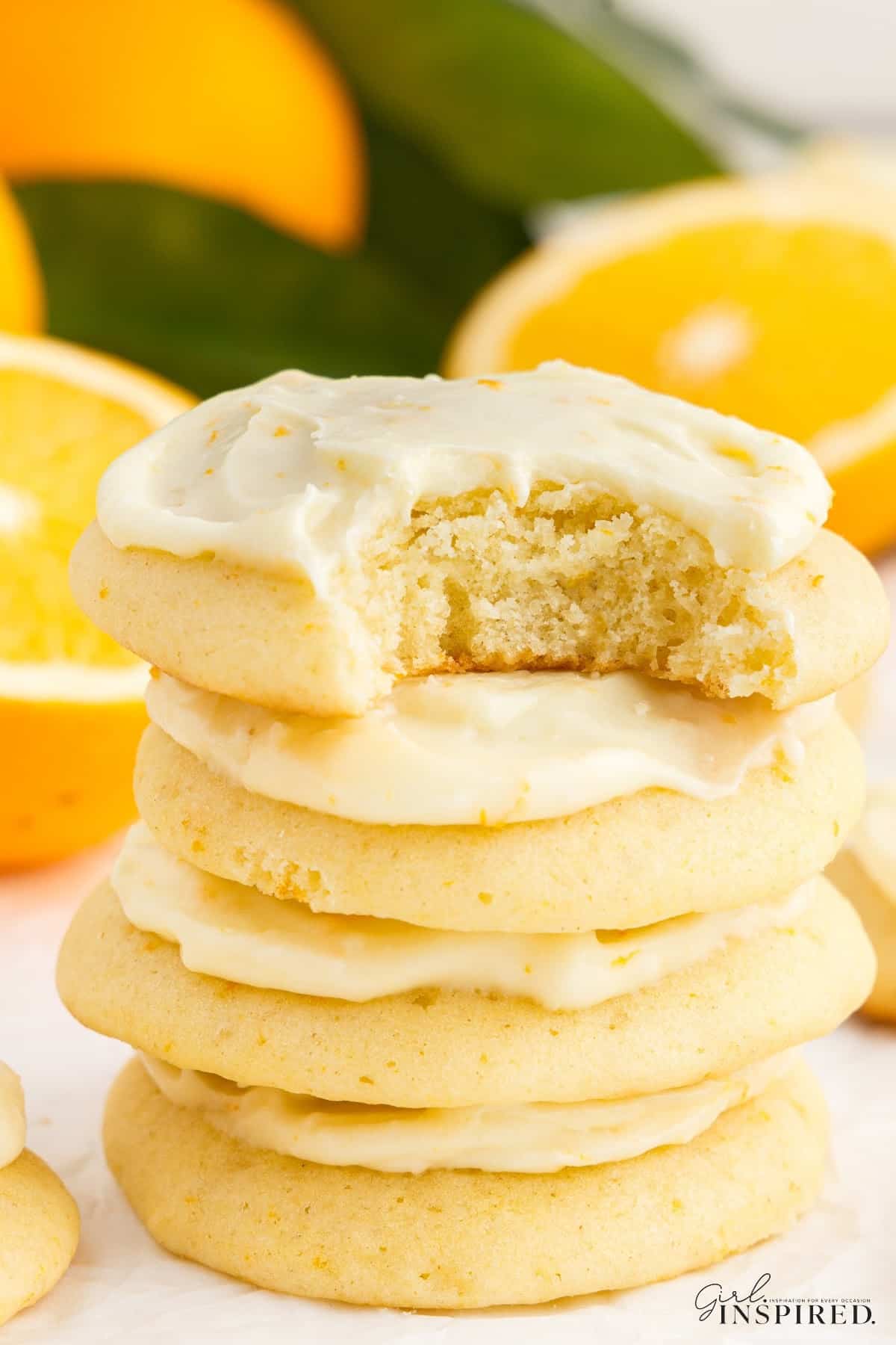 A stack of Orange Cookies with a bite taken from the top one.