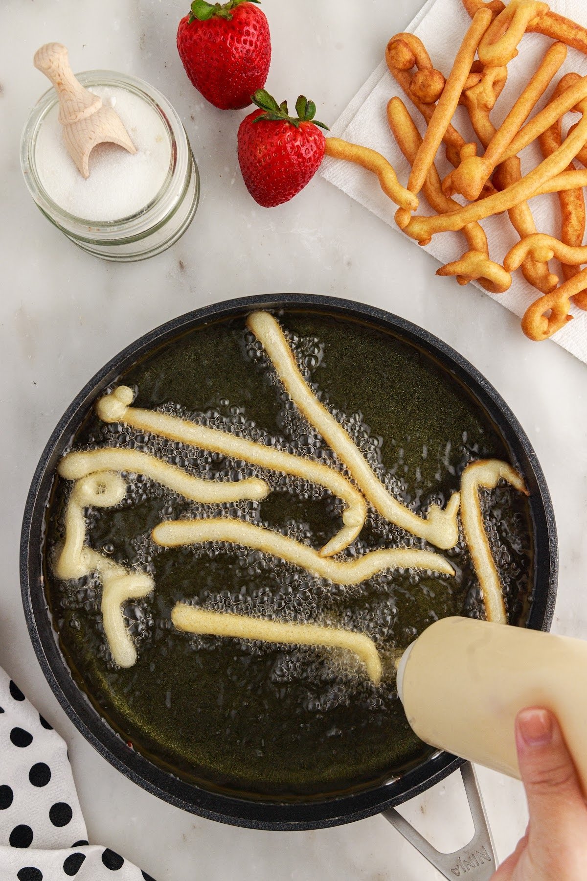 Funnel Cake Fries batter squeezed into a pan of oil.