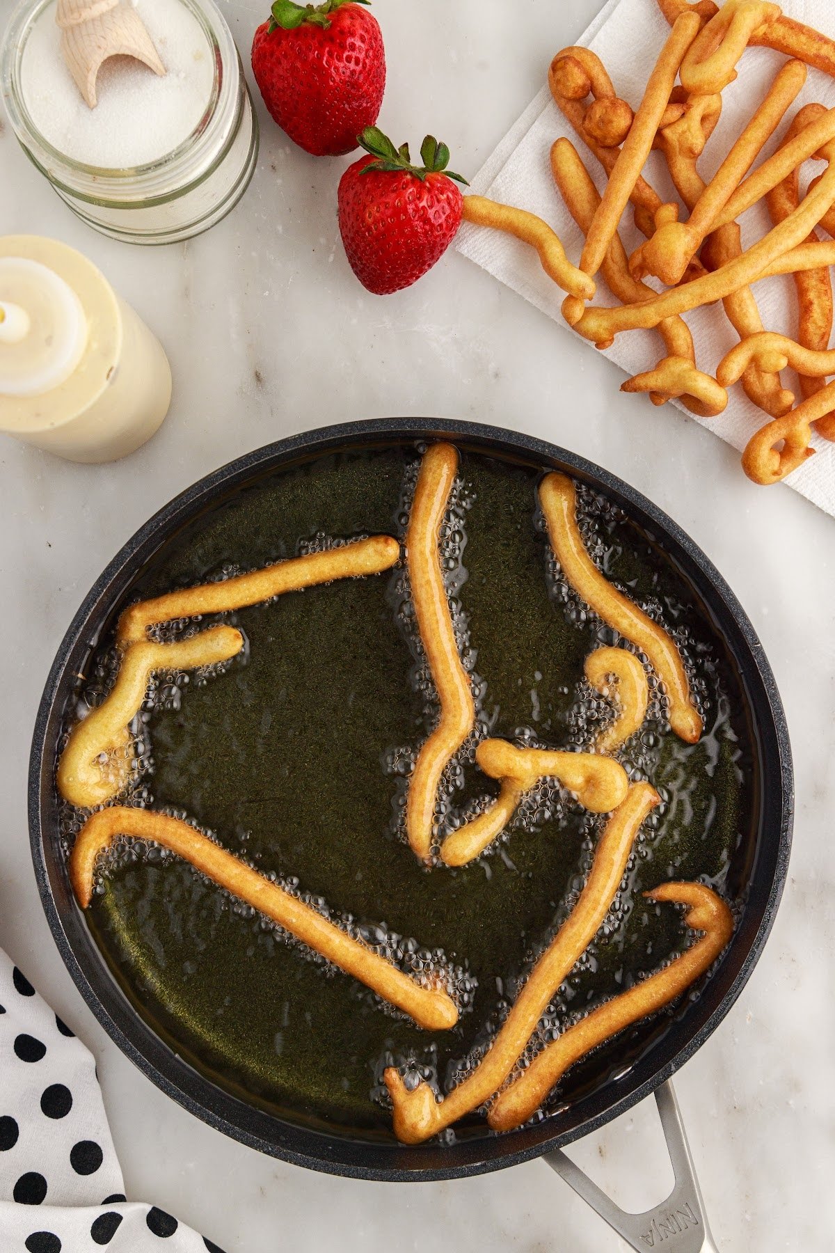 Funnel Cake Fries in a pan of oil.