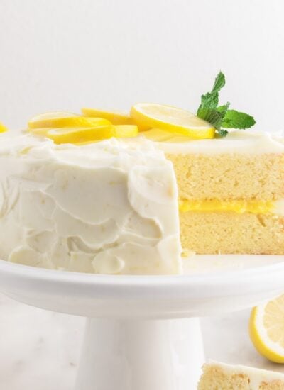 Front view of Lemon Curd Cake on a cake platter with a slice missing.