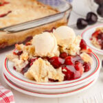 A serving of Cherry Dump Cake on a plate with ice cream.