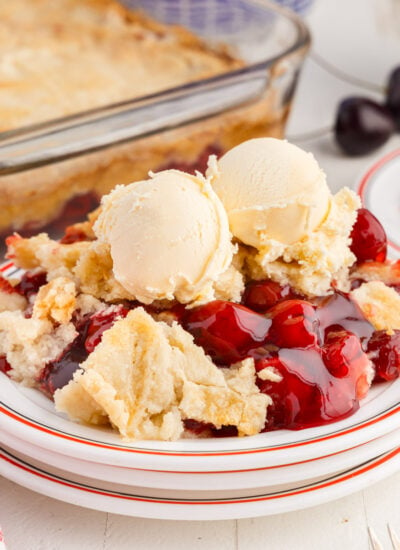 A serving of Cherry Dump Cake on a plate with ice cream.