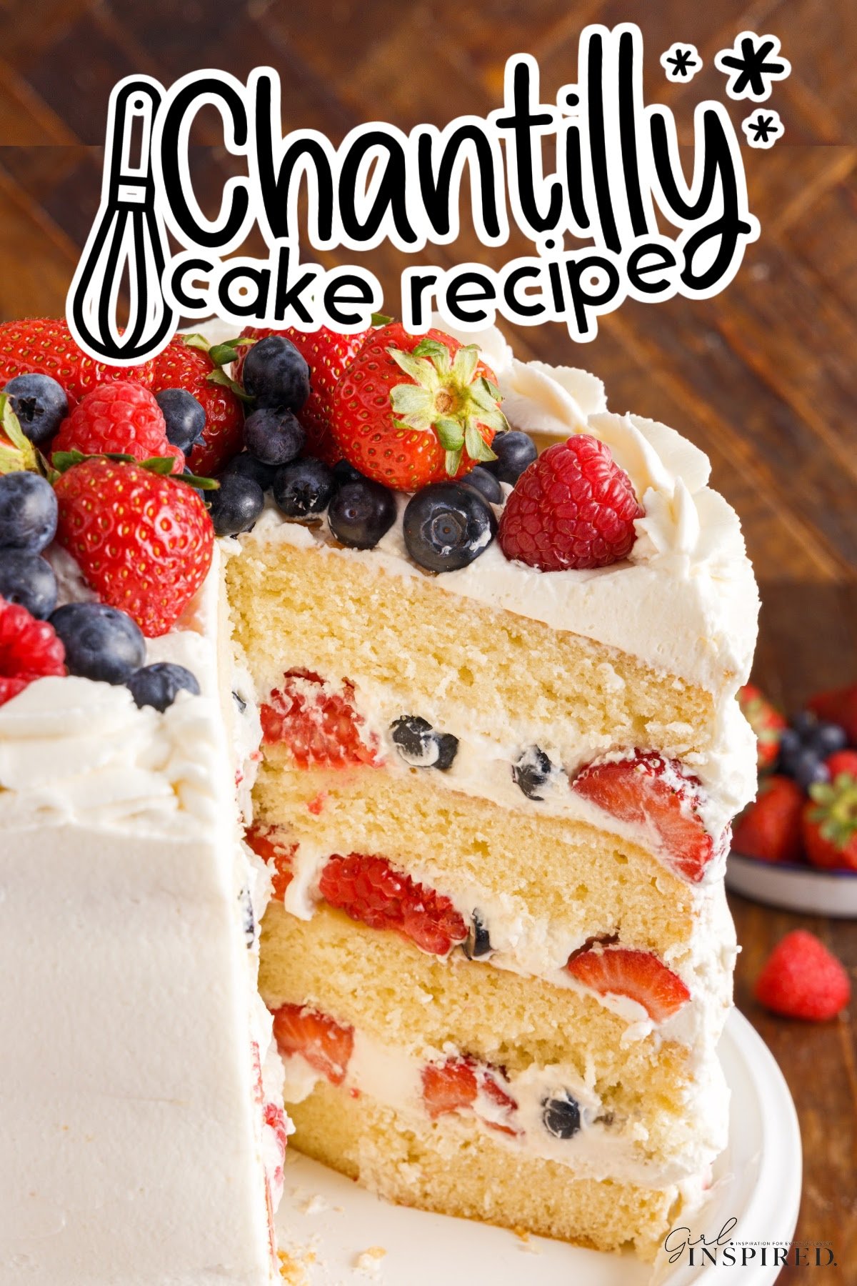 Layered Chantilly Cake with frosting and berries in between the layers and a slice taken out with title overlay.