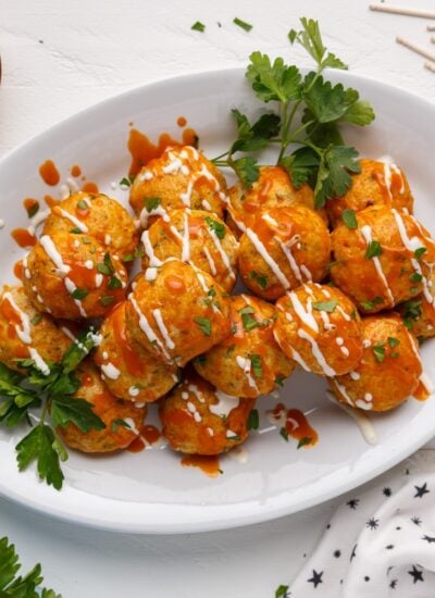 A pile of Buffalo Chicken Meatballs on a platter garnished with parsley.