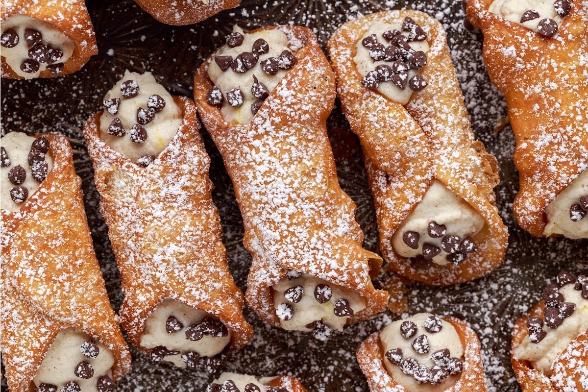Cannoli's dusted with powdered sugar and chocolate chips on the ends.