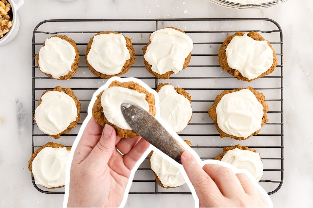Each cookie being topped with creamy frosting on a wire rack.