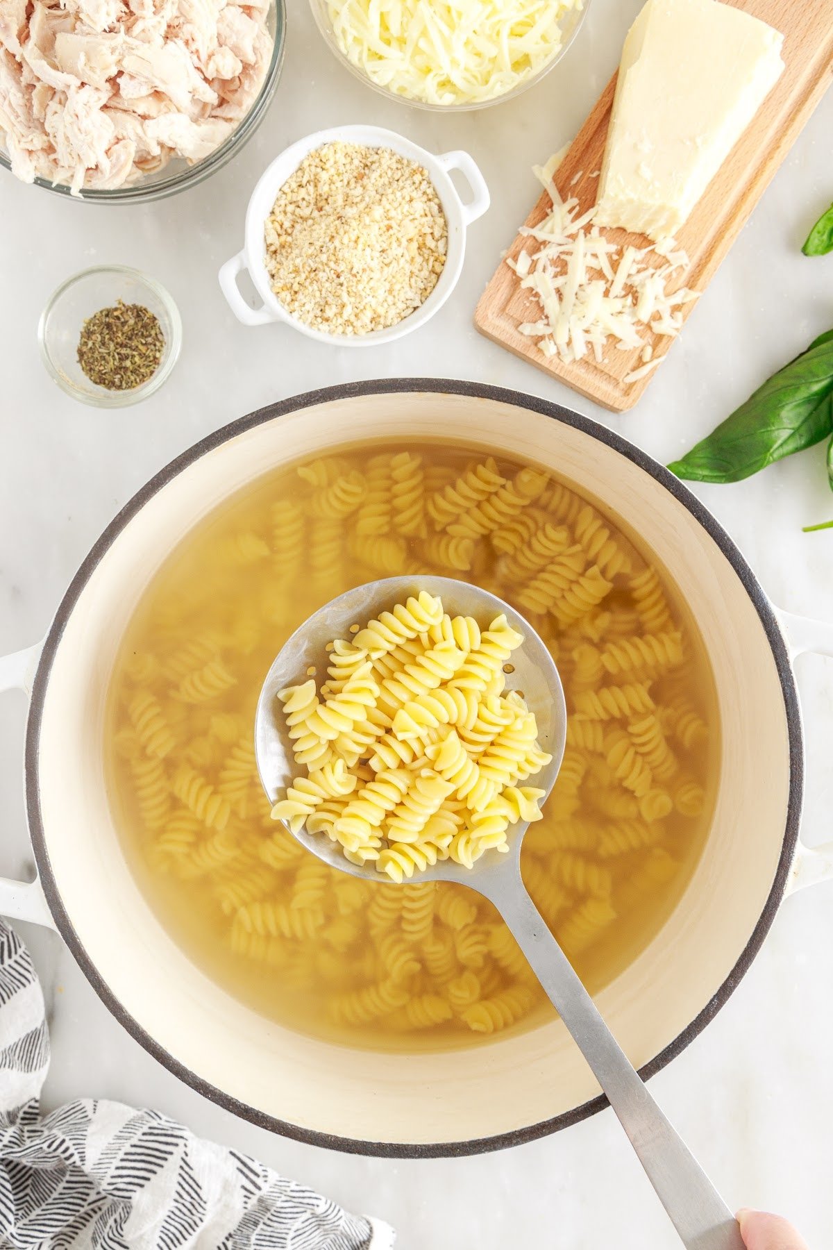 Cooked pasta in a large bowl with a spoon on top filled with noodles.
