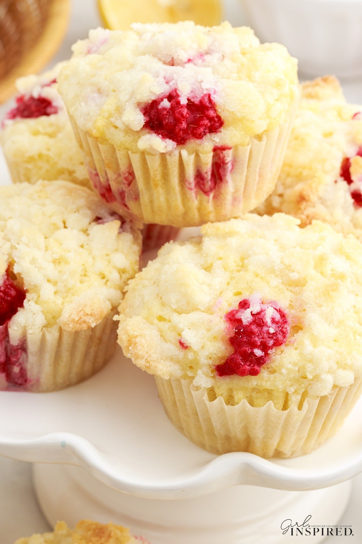 Lemon raspberry muffins stacked on a white cake plate.