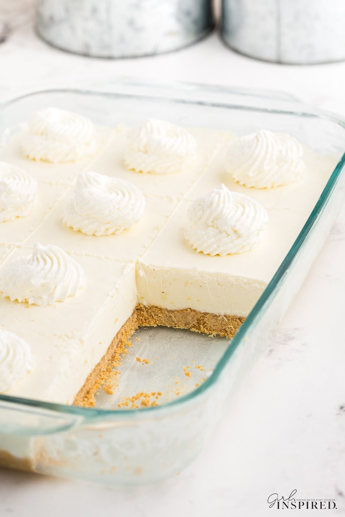 A dish full of no bake cheesecake bars, with one taken out.
