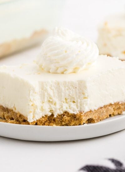 A no bake cheesecake bar with whipped cream on a plate.