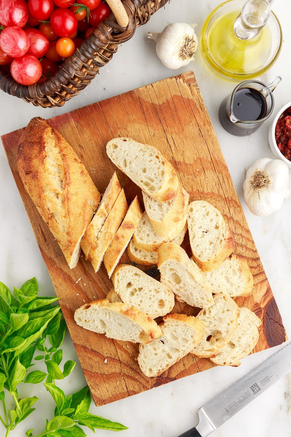 Sliced baguette loaf on a cutting board next to other ingredients.