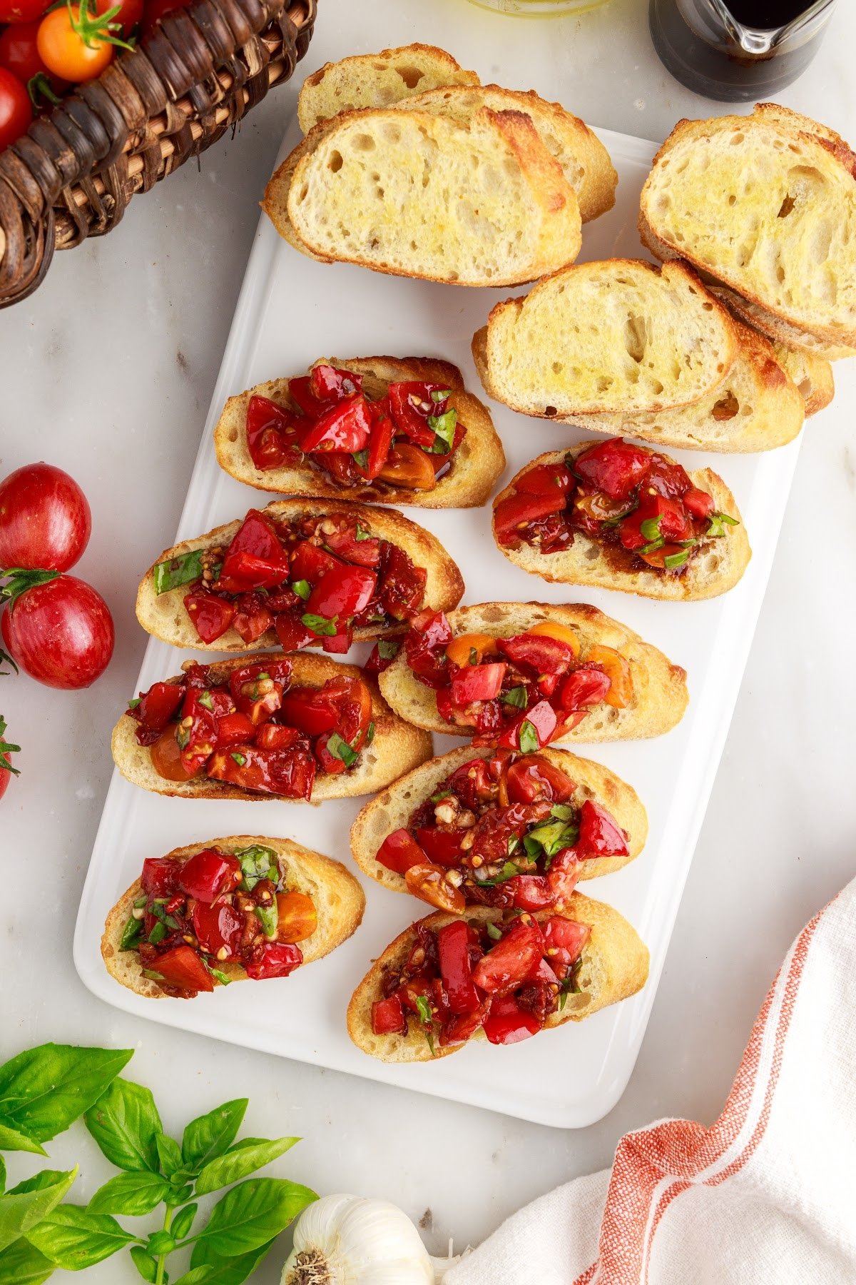 Sundried tomato bruschetta on a white serving platter next to bread slices.