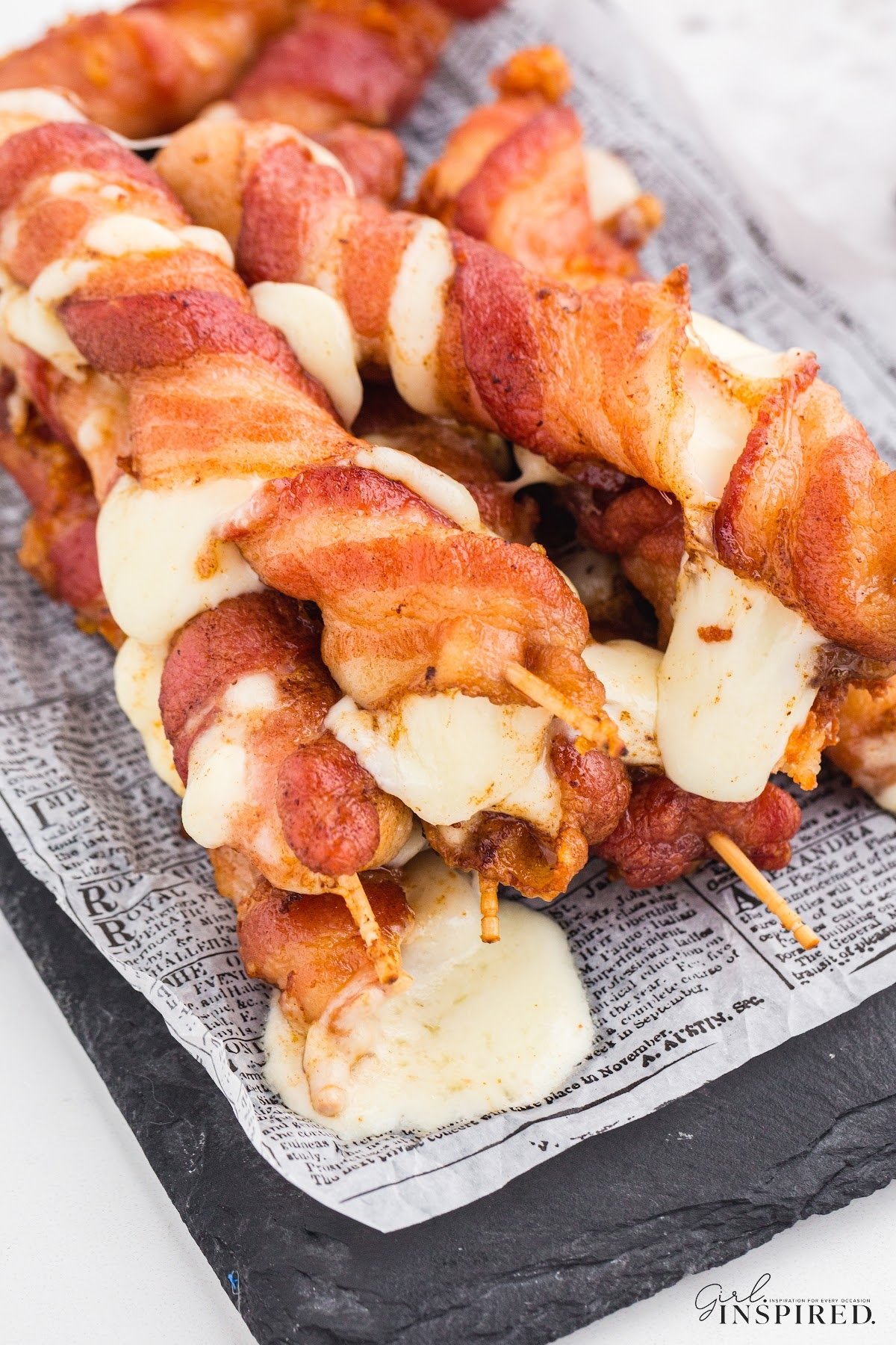 Bacon wrapped mozzarella sticks that have been deep fried with cheese oozing out.