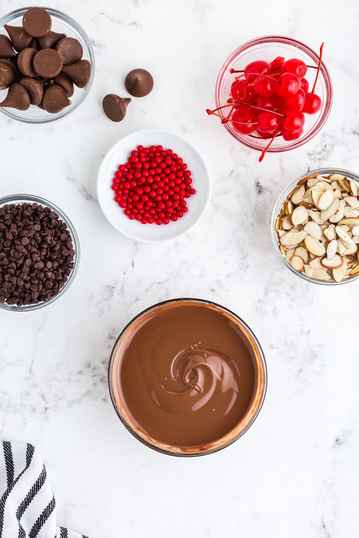 Melted milk chocolate in a bowl, with other ingredients surrounding.