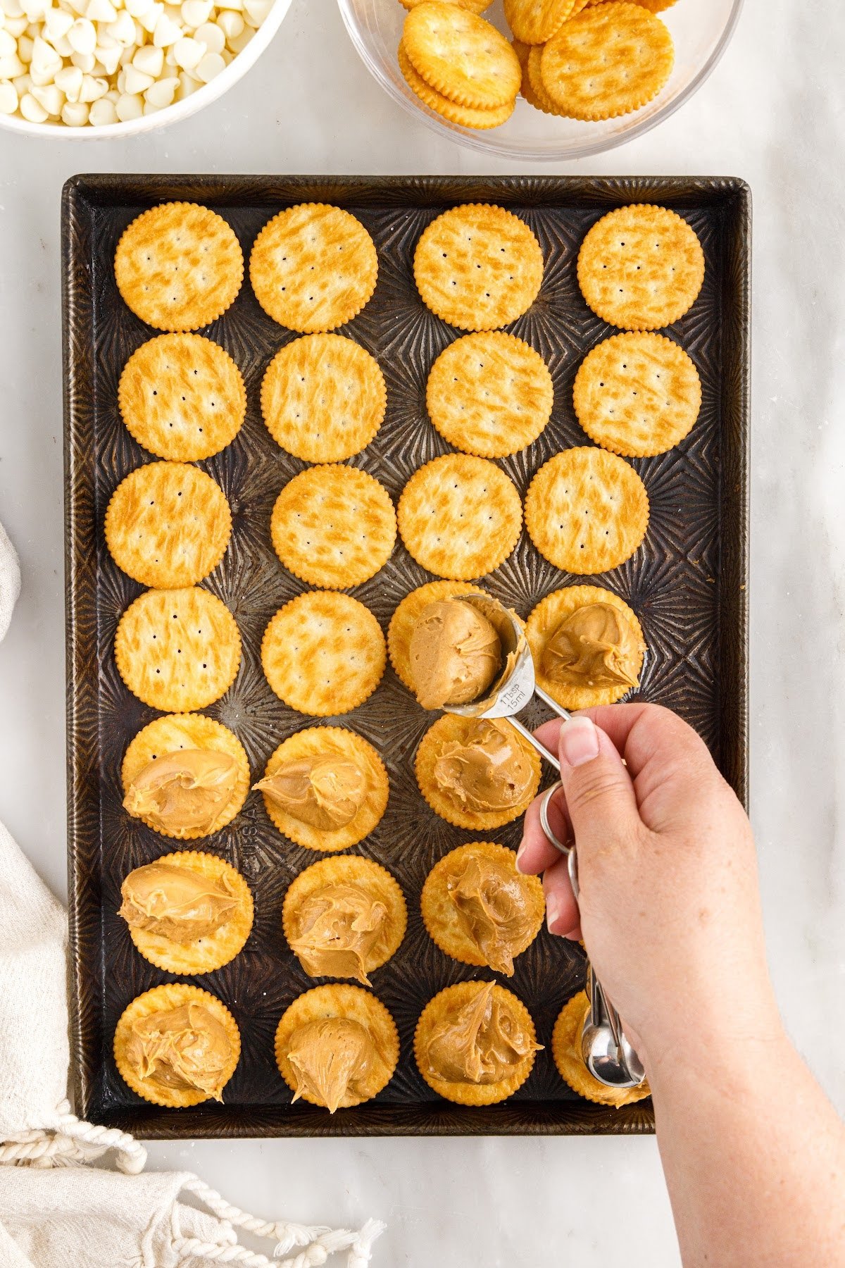 Spooning the peanut butter mixture on each cracker.