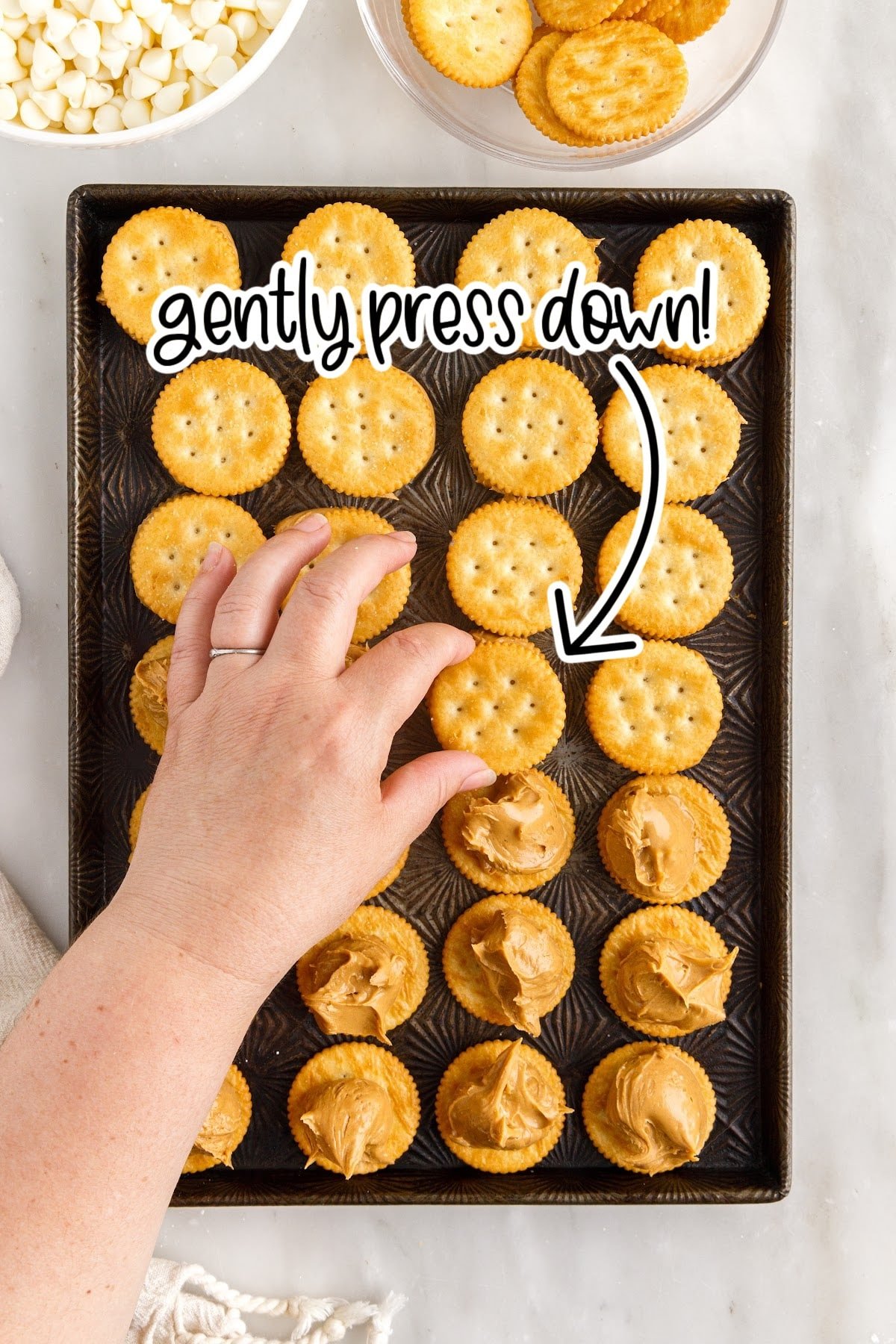 Placing the top cracker onto the peanut butter.