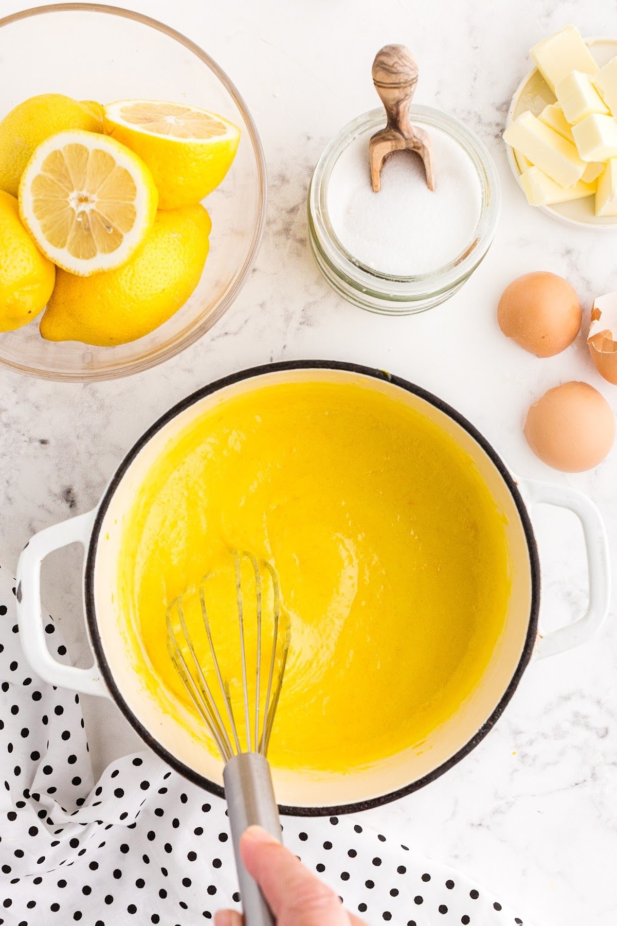 Lemon curd is cooked and creamy on the stove top in a pan.