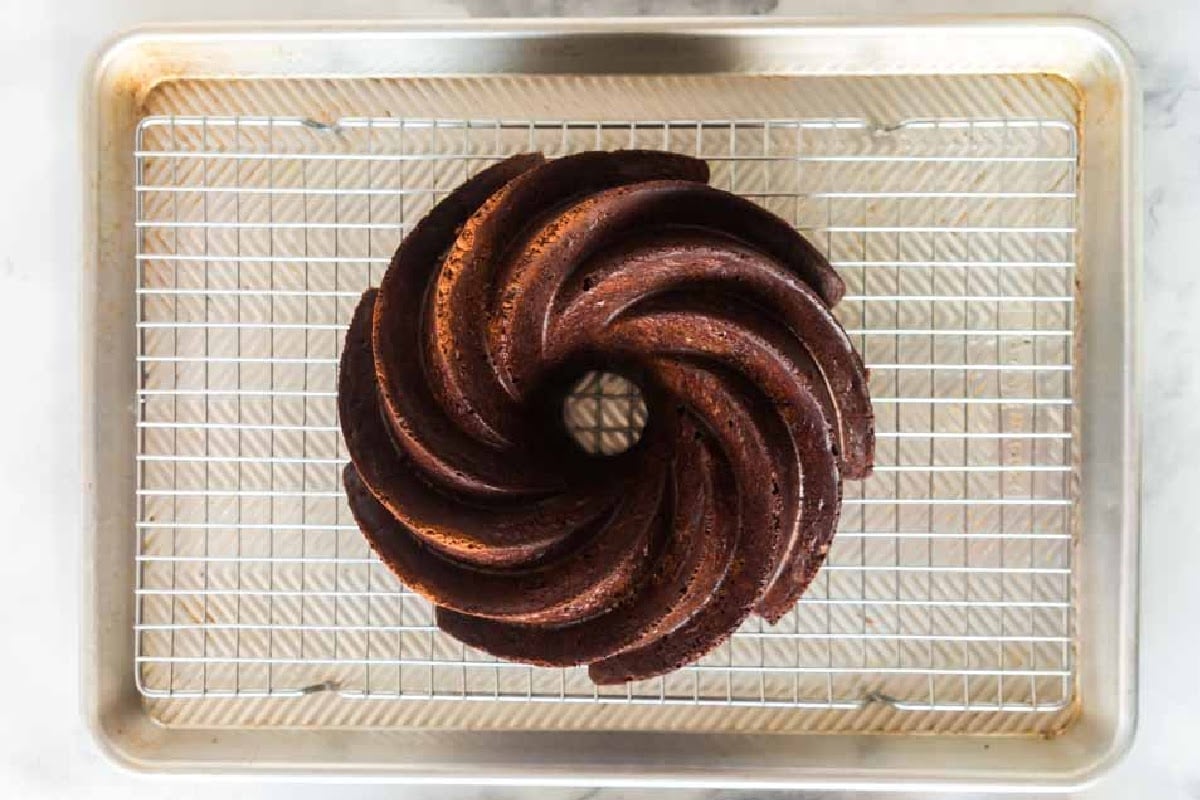 Overhead view of a cookie sheet with a cooling rack inside with Double Chocolate Fudge Cake on top.