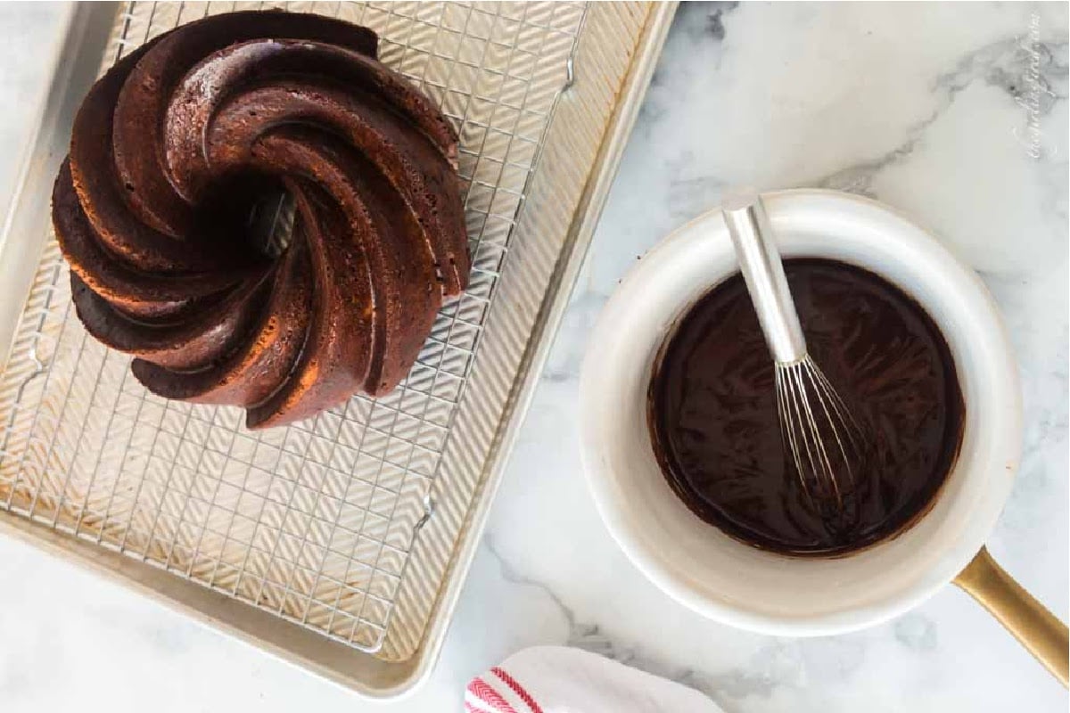 Double Chocolate Fudge Cake on a cooling rack next to icing.