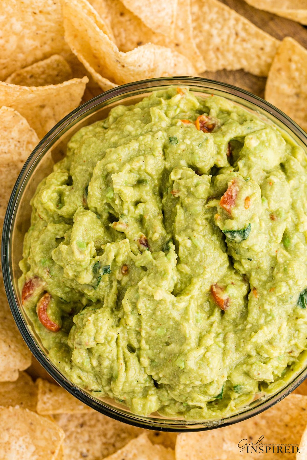 Bowl of guacamole with chips surrounding it.